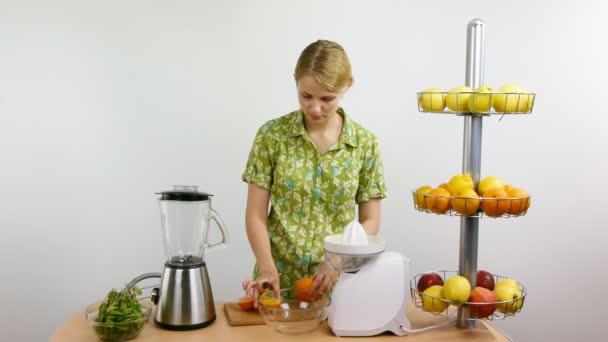 Mujer rubia joven corta naranjas para jugos — Vídeos de Stock