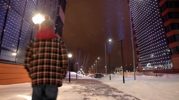 Kids running away near the modern high building at night in winter. — Stock Video