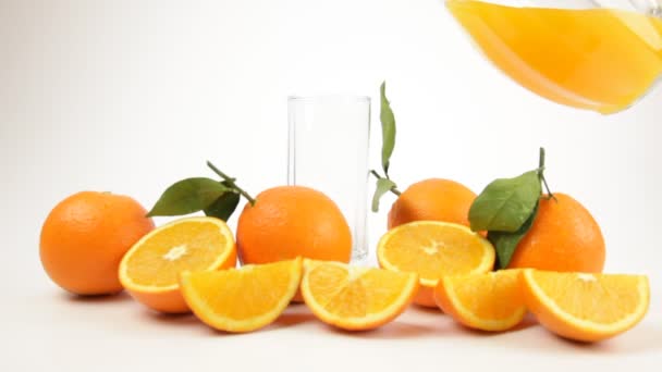 Наливая стакан свежевыжатого апельсинового сока из кувшина — стоковое видео