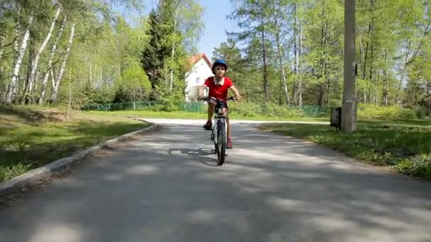 Kind fietsen - jongen paardrijden zijn fiets op de weg in de voorsteden. — Stockvideo