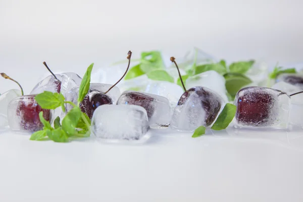 Cereja em cubos de gelo e hortelã em branco — Fotografia de Stock