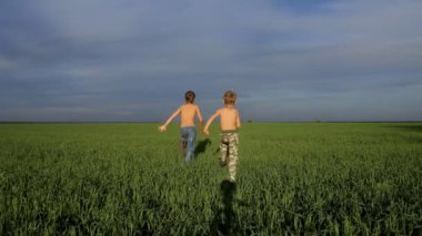 İki çocuk yeşil alanda yetişmeye çalışıyor.