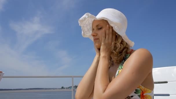 Menina bonita em chapéu aplicando protetor solar no rosto . — Vídeo de Stock