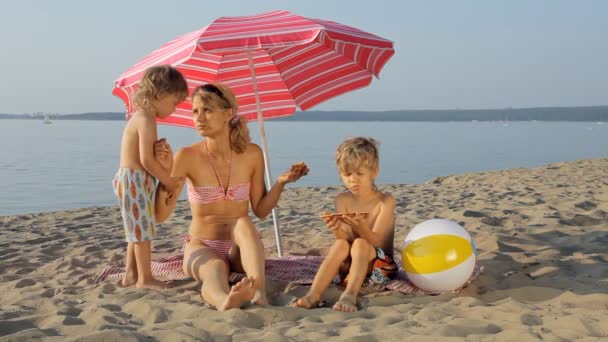 Kinder mit Mutter essen Pizza am Strand — Stockvideo