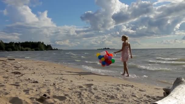 Mooi meisje met kleurrijke ballonnen wandelen op het strand — Stockvideo