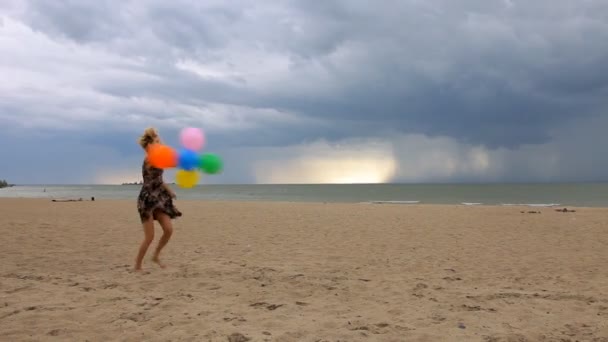 Glad ung kvinna med ballonger att ha kul på stranden — Stockvideo