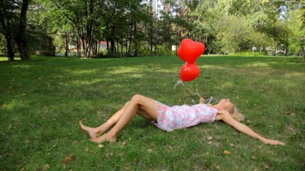 Szczęśliwa dziewczyna z czerwonym sercem balony na zielonej trawie — Wideo stockowe