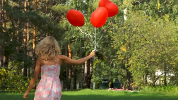 Lycklig tjej ha kul med hjärta ballonger utomhus — Stockvideo