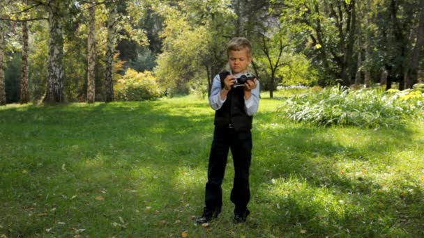 Jongen nemen van foto's met behulp van retro filmcamera in groen park — Stockvideo