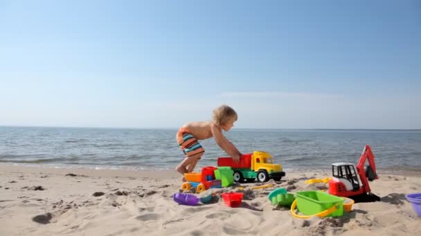 Petit garçon jouer avec des jouets sur la plage — Video