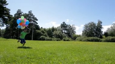 mutlu çocuk ile birçok renkli balon yeşil çimenlerin üzerinde çalışan