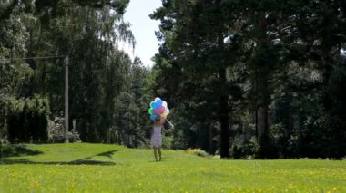 Birçok renkli balonlarla Park'ta yürüyordunuz elbiseli güzel kadın