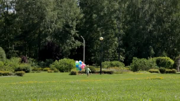 Niño feliz corriendo con muchos globos de colores — Vídeo de stock