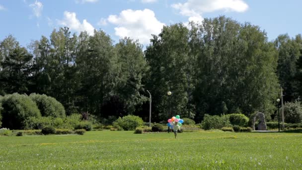 Pequeño niño corriendo y saltando con muchos globos de colores — Vídeos de Stock