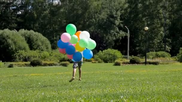 Ευτυχισμένος μικρό αγόρι που τρέχει με πολλά πολύχρωμα μπαλόνια — Αρχείο Βίντεο
