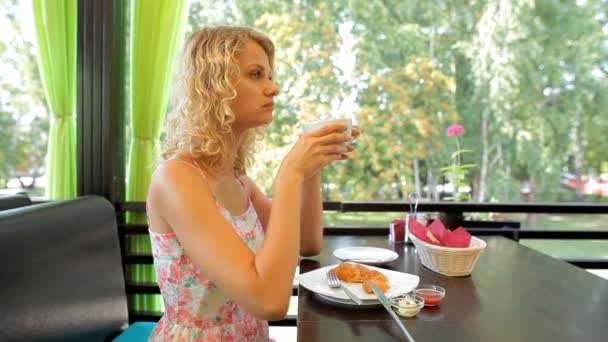 Ung kvinna äter frukost på café — Stockvideo