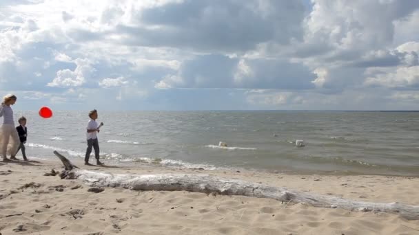 Молодая мать и трое детей с воздушными шарами прогуливаются по пляжу — стоковое видео