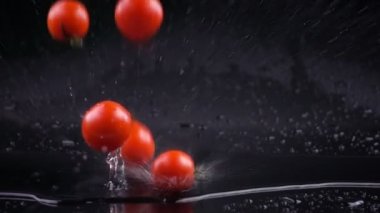 Ağır çekim domates su ile düşen siyah yüzey üzerinde damla.