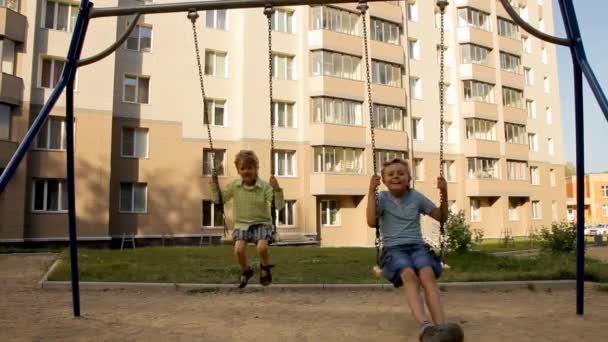 Crianças balançando no playground perto da casa — Vídeo de Stock