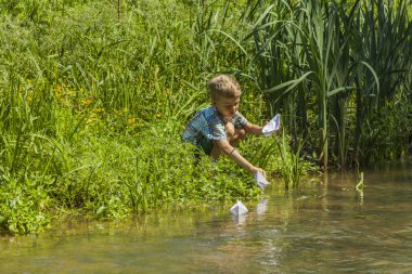 küçük çocuk bir nehir tarafından kağıt tekne ile oynarken