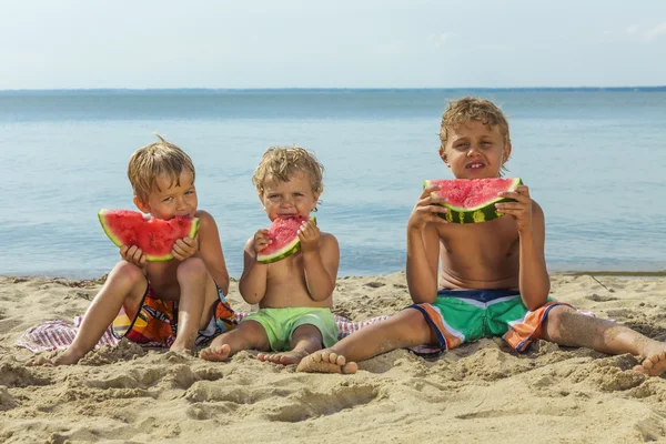 快乐的孩子在沙滩上吃西瓜大红色片. — 图库照片