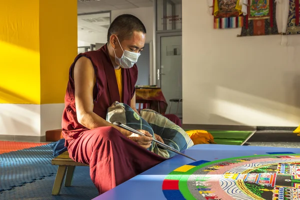 Tibetian monk constructing mandala from colored sand