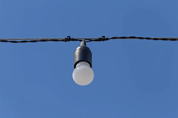 电灯泡挂在蓝色天空的电缆上 — 图库照片