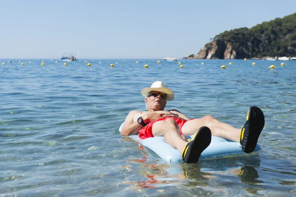 Retired man playing in sea water — Stock Photo, Image