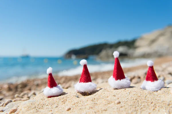 Hüte des Weihnachtsmannes am Strand — Stockfoto