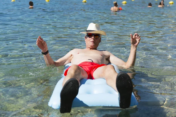 Retired man playing in sea water — Stock Photo, Image