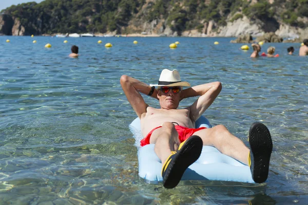 Retired man playing in sea water — Stock Photo, Image