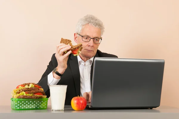 Senior business man eating bread — Stock Photo, Image