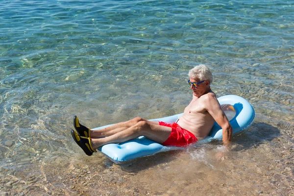 Retired man playing in sea water — Stock Photo, Image