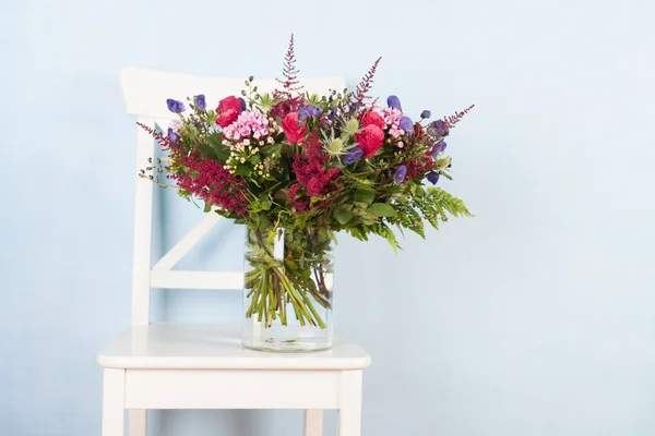 Blandad bukett blommor på stol — Stockfoto