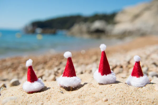 Hattar av Santa Claus på stranden — Stockfoto