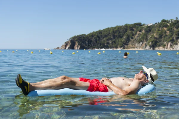 Nyugdíjas ember alszik a tenger víz ágy — Stock Fotó