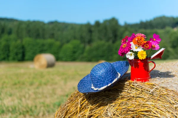 Bouquet flowers and summer hat in summer — Stock Photo, Image