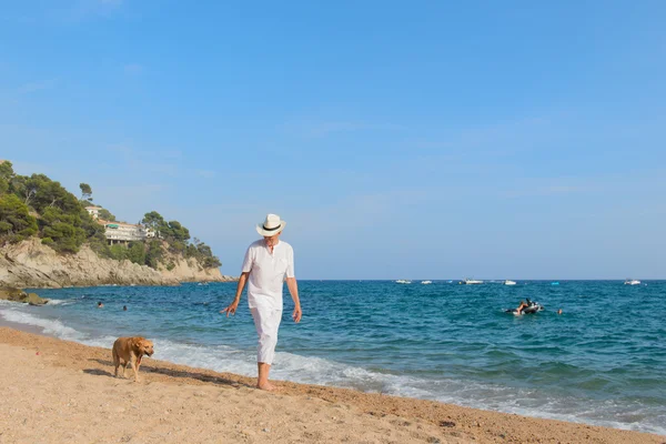 Pria senior dengan anjing di pantai — Stok Foto