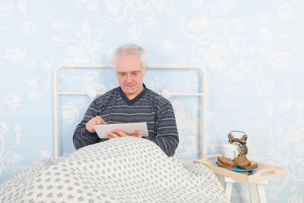 Reading digital tablet in bed — Stock Photo, Image