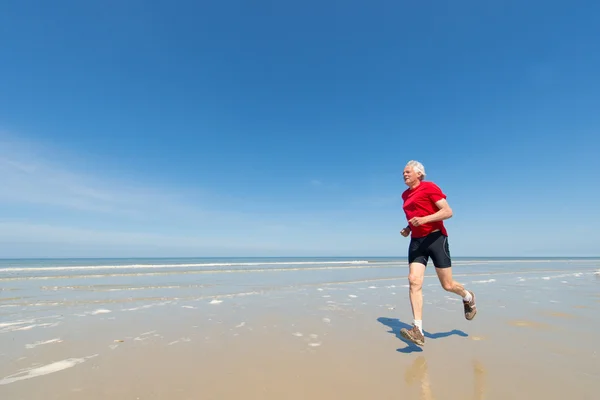 Starszy człowiek działa na plaży — Zdjęcie stockowe