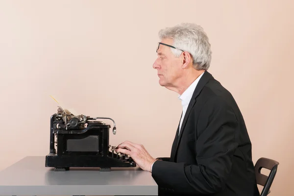 Чоловік, що працює з чорною друкарською машинкою — стокове фото
