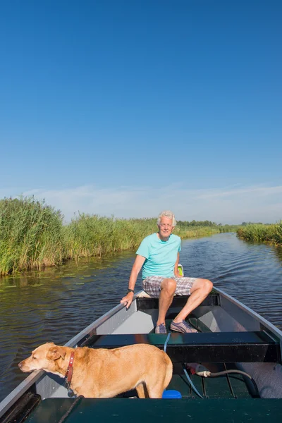 Starší muž se psem v motorovém člunu — Stock fotografie