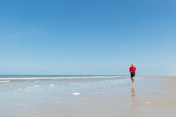 Homem mais velho correndo na praia — Fotografia de Stock