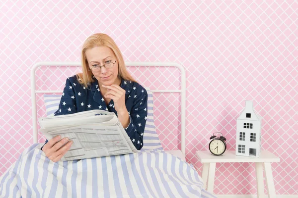 Mulher com jornais na cama — Fotografia de Stock