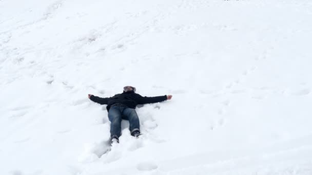 雪の中で横になっている幸せな男 — ストック動画