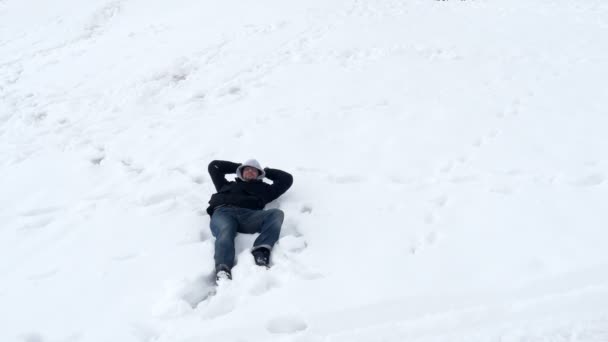 Hombre feliz yaciendo en la nieve — Vídeos de Stock
