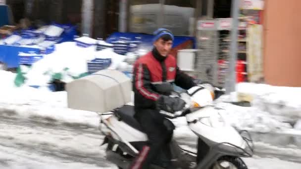 Courier van de scooter rijden op besneeuwde straat — Stockvideo