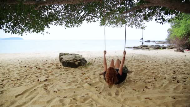 Девушка наслаждается на качелях на пляже — стоковое видео