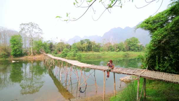 Toeristische meisje zit op bamboe brug — Stockvideo