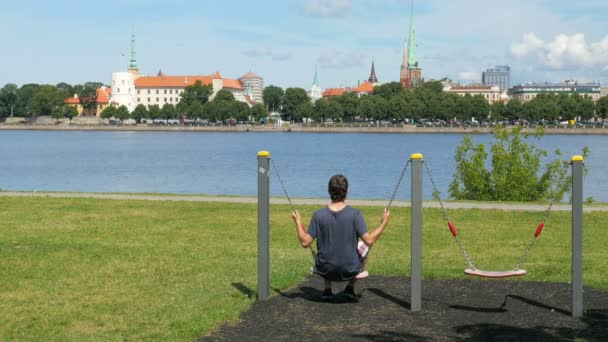 Man swinging on swing in Riga — Stock Video